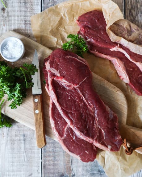 Два куски сирого стейка на столі